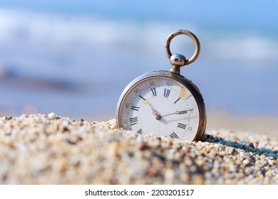 Antique pocket watch lost in the sand on the beach. Sands of time.