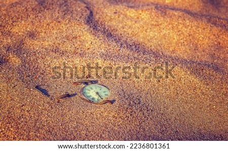 Antique rotten pocket watch buried partial in the sand.