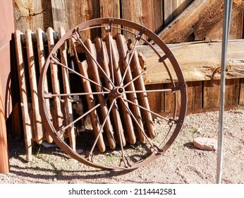 Antique rusty wagon wheel leaning against a barn in a ghost town in Arizona