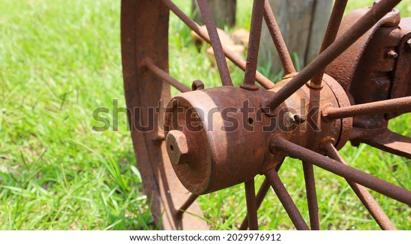 Antique rusty wheel hubs. Steel\
wheel hubs with large spokes of an old car on a green grass outdoor\
background with copy space. Choose to focus on close\
subjects.