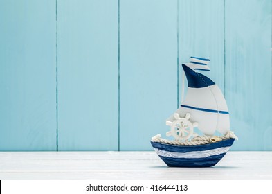 Antique Sail Boat Toy Model With Ship'wheel, Rope And Seashell On White And Blue Wooden Background - Nautical Background