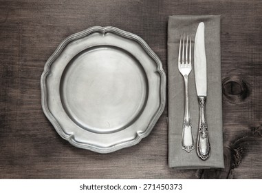 Antique silver cutlery and vintage tin plate on old wooden background