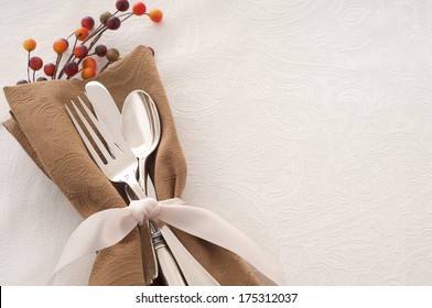 Antique Silverware Place Setting in a Brown Napkin and Tied with Ribbon on White Background, a Table Cloth with space or Room for text, Copy, words