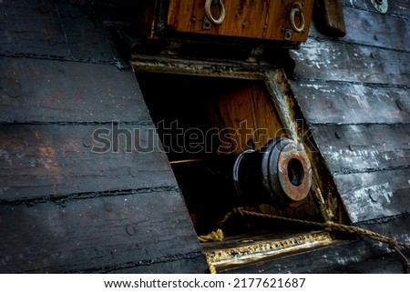 Antique six pound cannon pointing out of the hatch from the outside of a historic sailing war ship and galleon as a military naval battle concept 