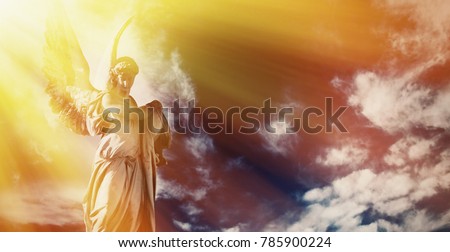Antique sstatue of wonderful angel in the rays of the sunl on sky background (architecture, sculpture, religion, faith concept)