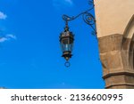 Antique street lighting lantern on the wall of the house against the blue sky