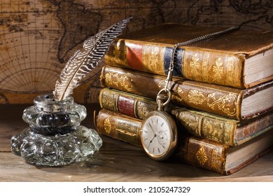 Antique table with books, pen, inkwell and pocket watch. Old map on background. Concept on the theme of history.