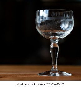 Antique Transparent Glass Wine Glass On A Black Background. Crystal Glass With Engraving. Glass Close-up