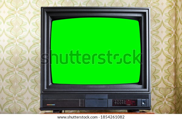 Antique TV\
with green screen on an antique wooden cabinet, old design in a\
house in the style of the 1980s and\
1990s.
