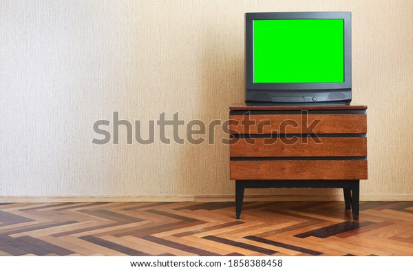 Antique TV with green screen on an antique
wooden cabinet, old design in a house in the style of the 1980s and
1990s.Interior in the style of the
USSR.