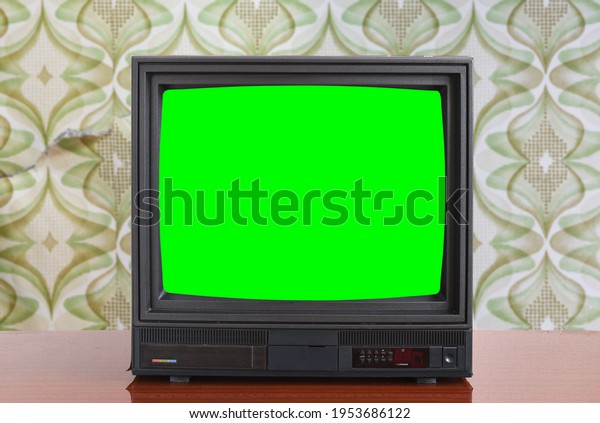 Antique TV\
with green screen on an antique wooden cabinet, old design in a\
house in the style of the 1980s and\
1990s.	