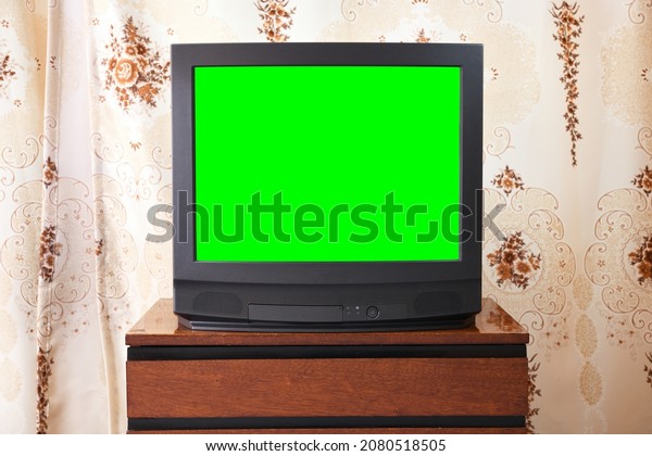 Antique TV with green screen on an antique\
wooden cabinet, old design in a house in the style of the 1980s and\
1990s.Interior in the style of the\
USSR.