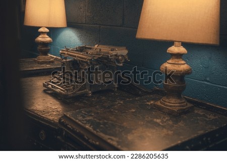 Antique type writer in vintage cafe, Chattanooga TN. Dark vibes with warm colors featuring vintage lamps and retro typewriter. Blue walls with weathered and worn antique desk.