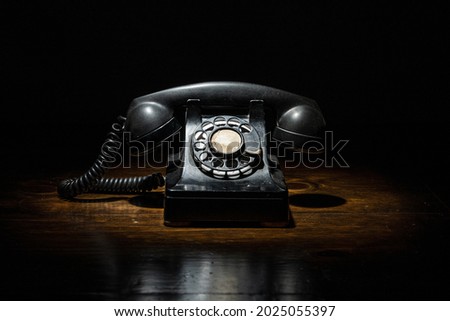 Antique Vintage Black Timey Old Rotary Phone in Dark Contrasty Moody Light Overhead Spot Light on Wood Table Stockfoto © 