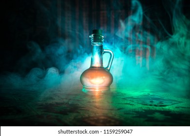 Antique and vintage glass bottle on dark foggy background with light. Poison or magic liquid concept.