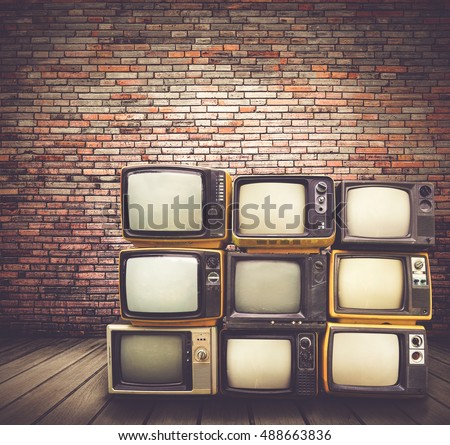 Antique and vintage style photo. retro televisions pile on floor in old room.