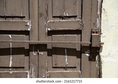 Antique Weathered Brown Wooden Door With A Chipped Paint And A Matching Wrought Iron Security Bar. 