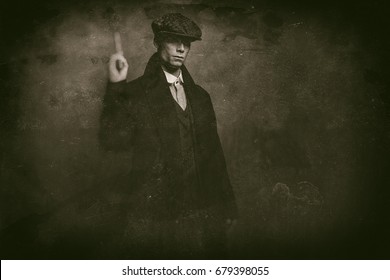 Antique wet plate photo of dangerous 1920s english gangster standing with gun.