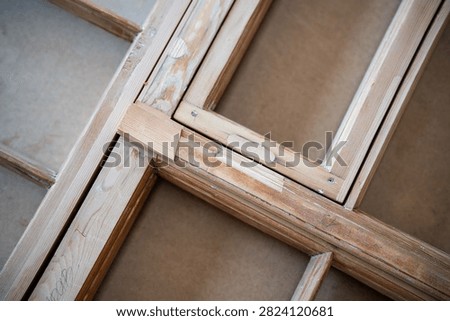 Antique window frame at worktable in restoration workshop undergoing renovation and reconstruction, stage of restoring wooden transom, insertion of patches made of wood same species, hardness and age.
