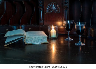 Antique Wood Desk And Book With Sherry Glasses By The Glow Of Candlelight.