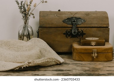 Antique wooden boxes and a vase of dry wildflowers on an old table. Rustic still life with memory about the past. Rusty style chest walnut box for jewelry. Magical faded background. Pirates theme.