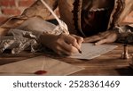 Antique young woman in renaissance dress sitting at table and writing letter with vintage quill pen with ink on old parchment papers sheet, close up shot.