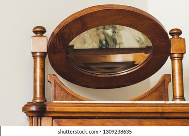 Antiques Inside A Home. A Wooden Bedside Table And A Folded Mirror Reflecting A Marble Slab.