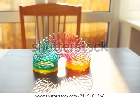 Anti-stress magic ring spring rainbow bounce toy on table in sunny room at home, selective focus. Stress relief and anti-anxiety toys concept