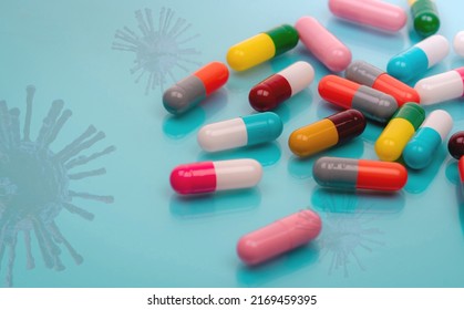 Antiviral Capsule Pills With Virus On Blue Background. Drug Development And New Drug Research For Treatment Emerging Infectious Diseases. Prescription Drugs. Pharmaceutical Industry. Pharmacology.