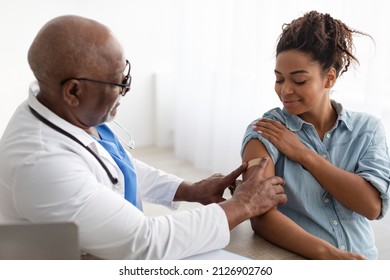 Antiviral Vaccination, Immunization. Mature medical worker sticking plaster bandage on patient's shoulder after injection in health centre. Pregnant black woman getting vaccine for Covid prevention - Powered by Shutterstock