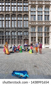 Antwerp, Belgium - 05 15 2016: A Colorful Street Band Plays Classical Music Instrument In Front Of Historical Buildings In The Center Of Antwerp. The Spectators Leave Coins In An Empty Violin Case