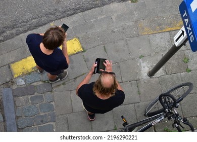 ANTWERP, BELGIUM - 08 28 2022: Top View Of Two Men Using Their Cellphones, One Man With Bald Head