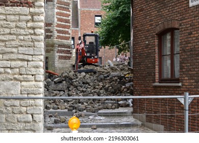 ANTWERP, BELGIUM - 08 28 2022: Small Excavator Stands On A Pile Of Cobblestone Rubble In A Small Alley Blocked By Steel Fences In The City Centre Of Antwerp