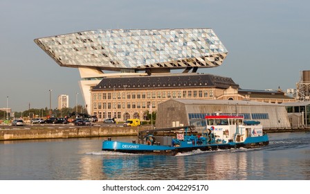 Antwerp, Belgium - 24 May 2018: A view on the Antwerp Port House building from Zaha Hadid just after sunrise with a boat passing by on the river Schelde.
