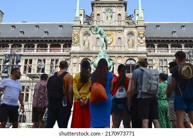 Antwerp city, Province Antwerp, Belgium - June 18, 2022: 10 tourists listening to the story told by the tour guide about symbol of Antwerp. Naked man throwing a hand from a giant in the river