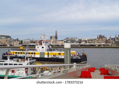 Antwerp/Belgium - July 2017: Commercial boat with people on river Scheldt. Cityscape with historical building and Antwerp cathedral. Waterfront view.