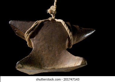 An Anvil Hanging By A Frayed Rope And Isolated On Black.
