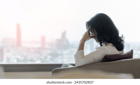 Anxiety disorder menopause woman with mental health illness, stressful depressed aging businesswoman female person with headache and migraine sitting tiredly at home with city background - Powered by Shutterstock