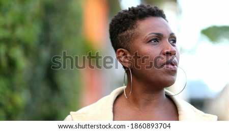 Anxious African woman walking outside. Black person ruminating thoughts