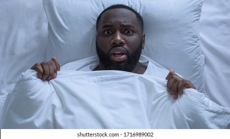 Anxious afro-american man lying in bed feeling that he has forgotten something
 - Shutterstock ID 1716989002