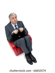 Anxious businessman sitting in a small armchair.