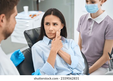 Anxious client complaining to stomatologist on sharp and sudden pain - Powered by Shutterstock