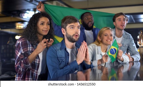 Anxious football fans with Brazilian flags supporting national team in game - Powered by Shutterstock