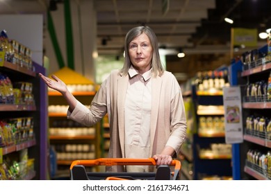 Anxious and frustrated retired woman in a grocery store near the shelves with expensive goods
