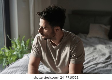 Anxious man at home sitting on bed and looking away - Powered by Shutterstock