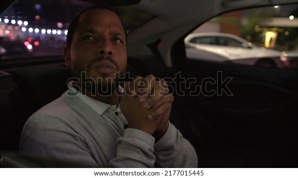 Anxious\
person in car backseat commuting at night after work inside taxi\
cab. Worried emotion of one black man inside\
car
