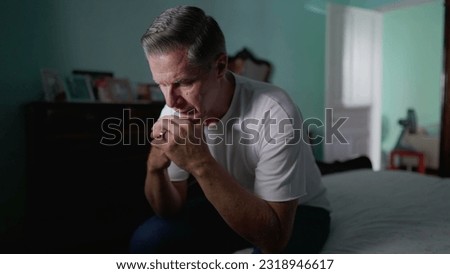 Anxious preoccupied older man sits by bedside feeling worry. Stressed desperate middle-aged person feeling suffering from mental illness