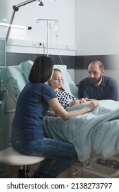 Anxious Stressed Couple Discussing About Little Girl Illness Evolution While In Pediatric Hospital Patient Recovery Ward Room. Worried Nervous Young Parents Talking About Healthcare Treatment.