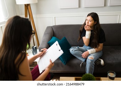 Anxious Teenage Girl With A Bandaged Wrist Biting Her Nails And Talking About A Suicide Attempt With A Psychologist