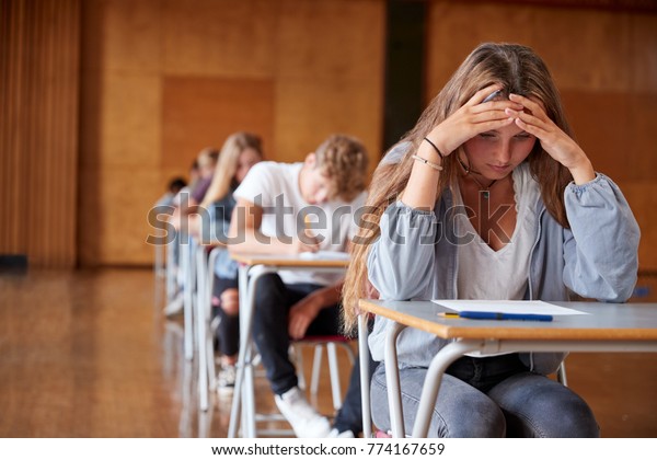 Anxious Teenage Student Sitting Examination In\
School Hall